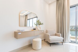 A modern bathroom with a vanity, a round stool, and a chair.