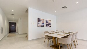 Un comedor moderno con una mesa de mármol, seis sillas y un cuadro abstracto en la pared.