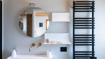 Een badkamer met een wit wastafel, een spiegel en een zwarte handdoekhouder.