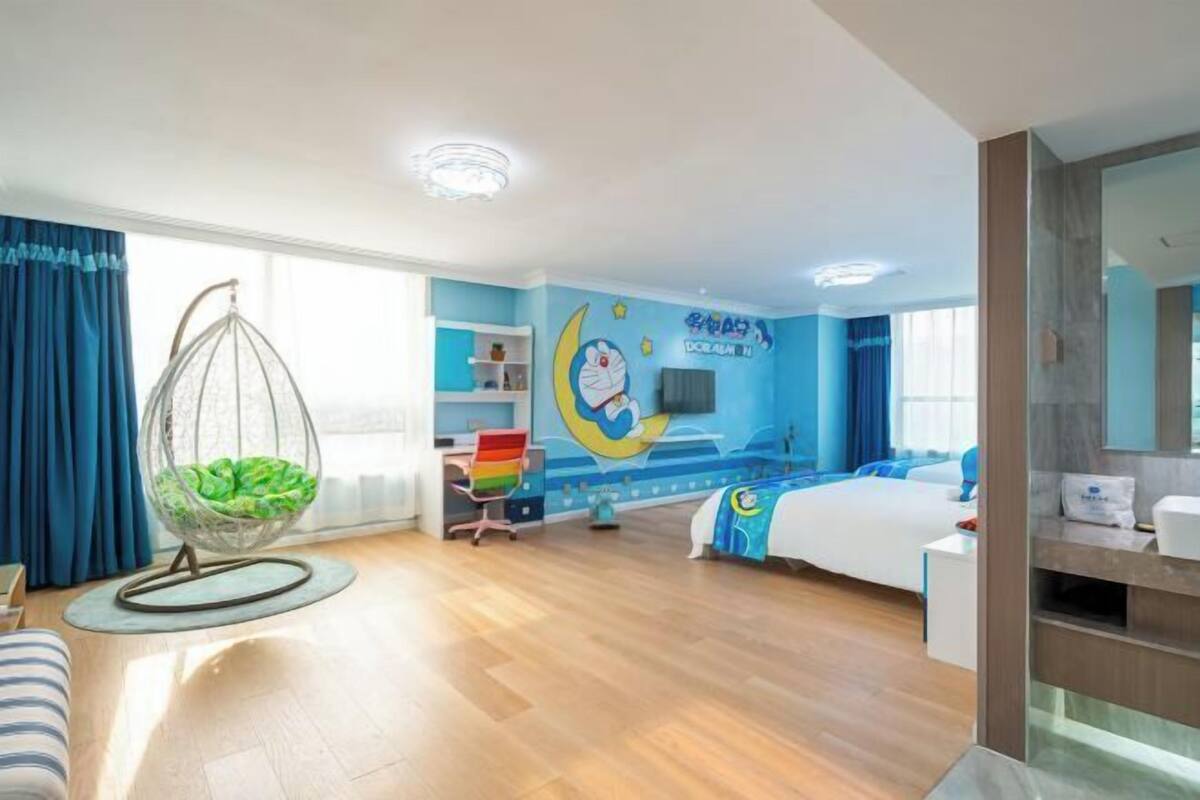A child's bedroom with a hanging chair, a bed, a desk, and a wall with a cartoon character.