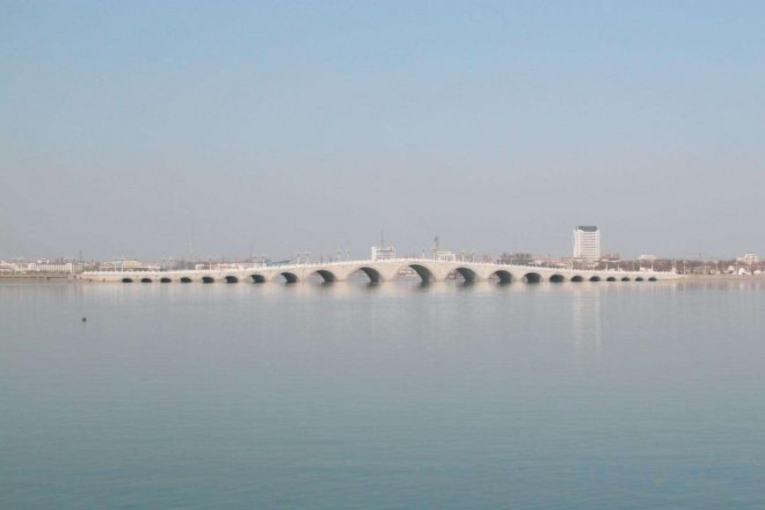 A bridge over calm water with a clear sky.