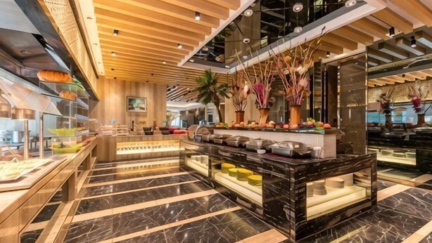 Un hall de hotel con piso de mármol, un mostrador de recepción central y una exhibición de alimentos.
