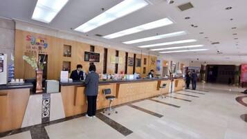 Zona de recepción de hotel con mostrador, área de espera y directorio a la vista.