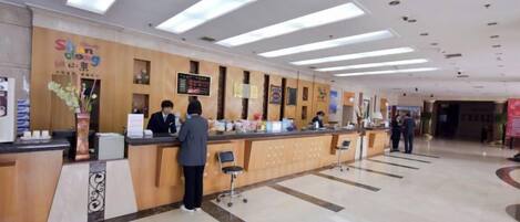 A hotel reception area with a reception desk, a waiting area, and a visible directory.