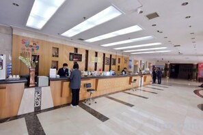 Zona de recepción de hotel con mostrador, área de espera y directorio a la vista.