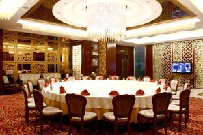 Une salle de conférence équipée d’une table ronde, de chaises et d’un grand lustre.