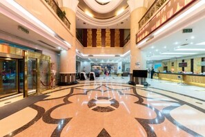 A spacious lobby with a central marble floor, a reception desk, and a staircase leading to upper floors. - Liaocheng Yuelu Hotel (Liaocheng)