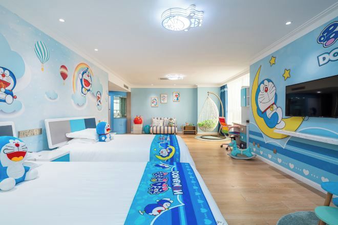 A children's room with a long bed, a TV, and a mural with cartoon characters.