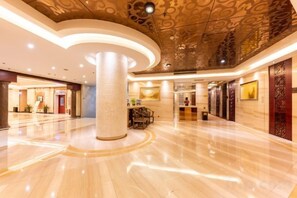 Un vestíbulo espacioso con piso pulido, una columna central y un techo decorativo.
