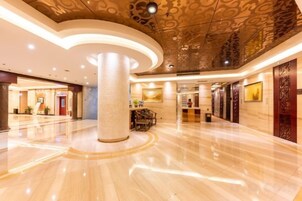Un vestíbulo espacioso con piso pulido, una columna central y un techo decorativo.