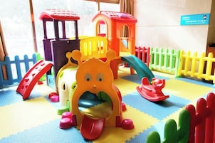 Un área de juegos infantiles con un tobogán, estructuras para escalar y una casa de juegos colorida.