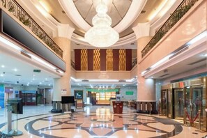 A spacious lobby with a central chandelier, a reception desk, and a check-in counter. - Liaocheng Yuelu Hotel (Liaocheng)