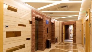Un pasillo de hotel con suelo de mármol, paneles de madera y un diseño moderno en el techo.