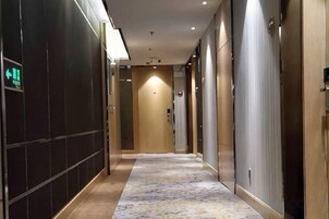 Pasillo de hotel con alfombra estampada, puertas a ambos lados y un letrero que indica una salida.