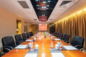 Une salle de conférence équipée d’une longue table, de chaises et d’un écran de projection.