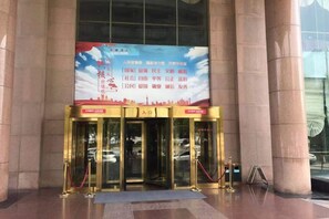 A hotel entrance with a large banner, glass doors, and a red rope barrier. - Liaocheng Yuelu Hotel (Liaocheng)