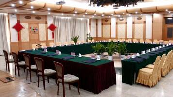 A conference room with a long table, chairs, and a stage.