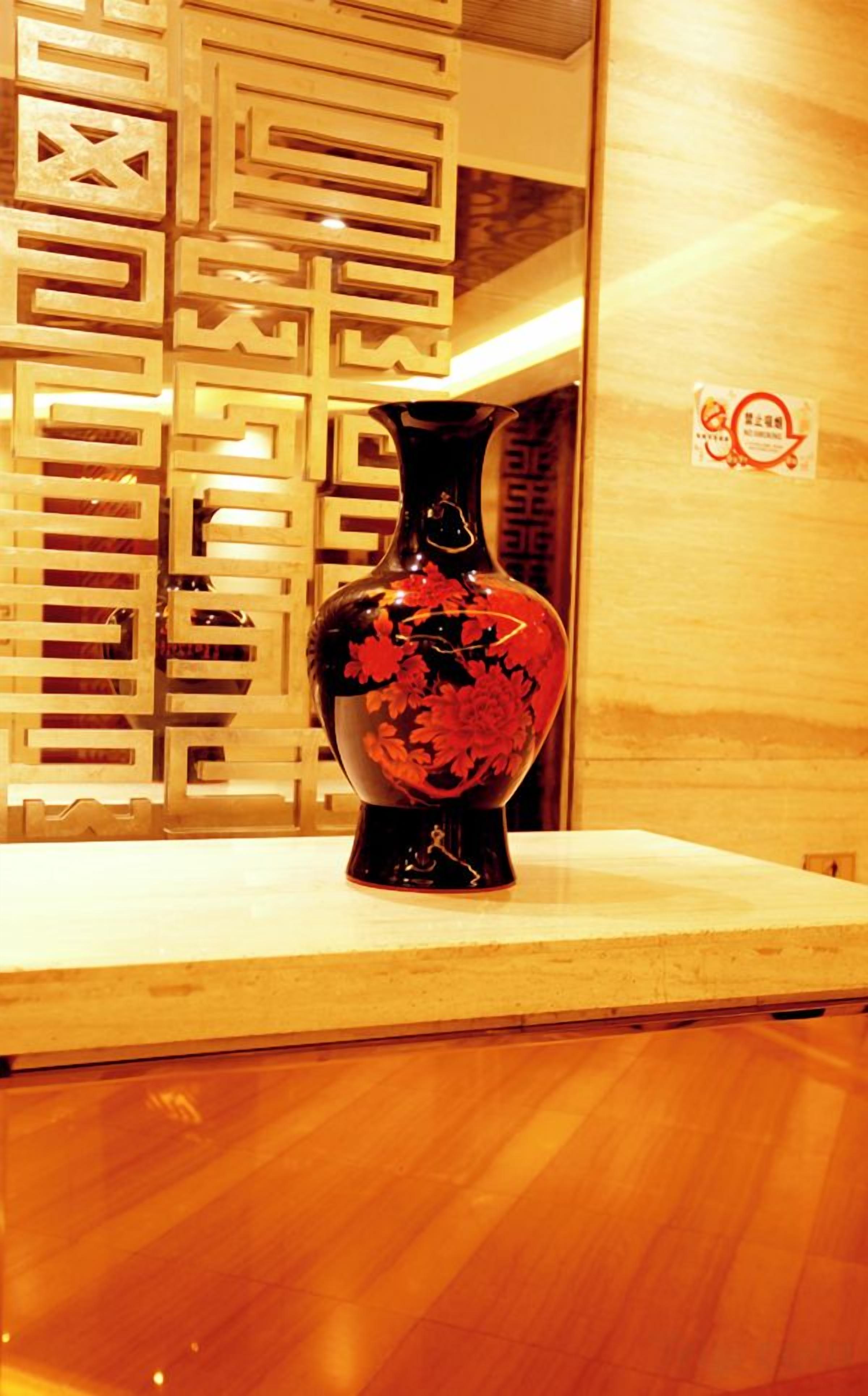 Un vase orné de motifs floraux, posé sur une surface en bois.