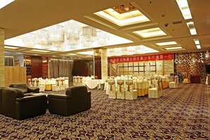 Un salón de banquetes con mesas redondas, sillas y una alfombra estampada.