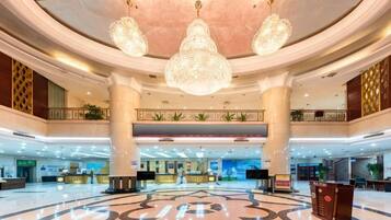 Un hall d’entrée spacieux, doté d’une fontaine centrale, de plusieurs comptoirs de réception et d’un plafond haut orné de lustres.