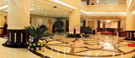 A spacious lobby with a central circular floor design, multiple levels, and a grand staircase.