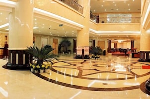 A spacious lobby with a central circular floor design, multiple levels, and a grand staircase.