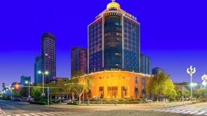 Un hotel moderno con una cúpula destacada y varios pisos, rodeado de otros edificios altos.
