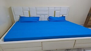 Een bed met een wit hoofdeinde en blauw beddengoed.