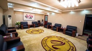 A conference room with a large table, multiple chairs, and a carpet with a hotel logo.