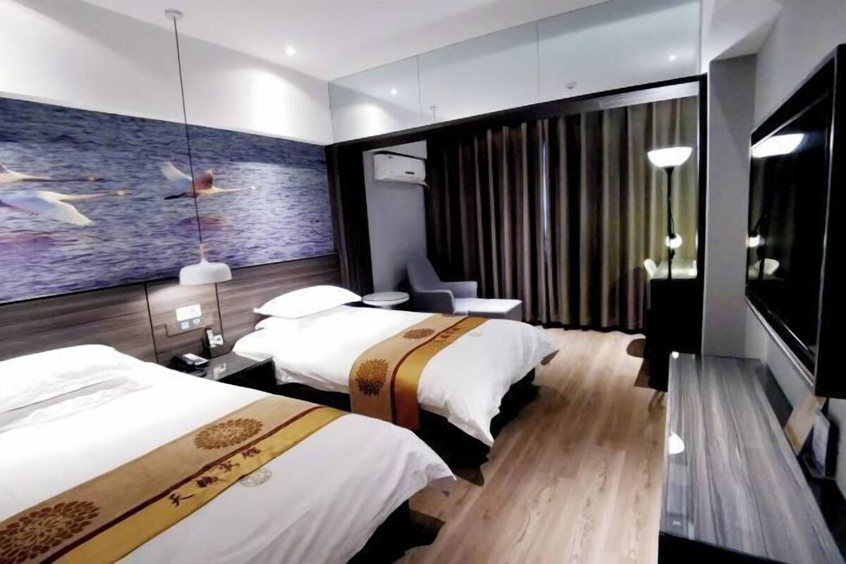 Habitación de hotel con dos camas, un mural grande en la pared, un televisor de pantalla plana y un diseño moderno.