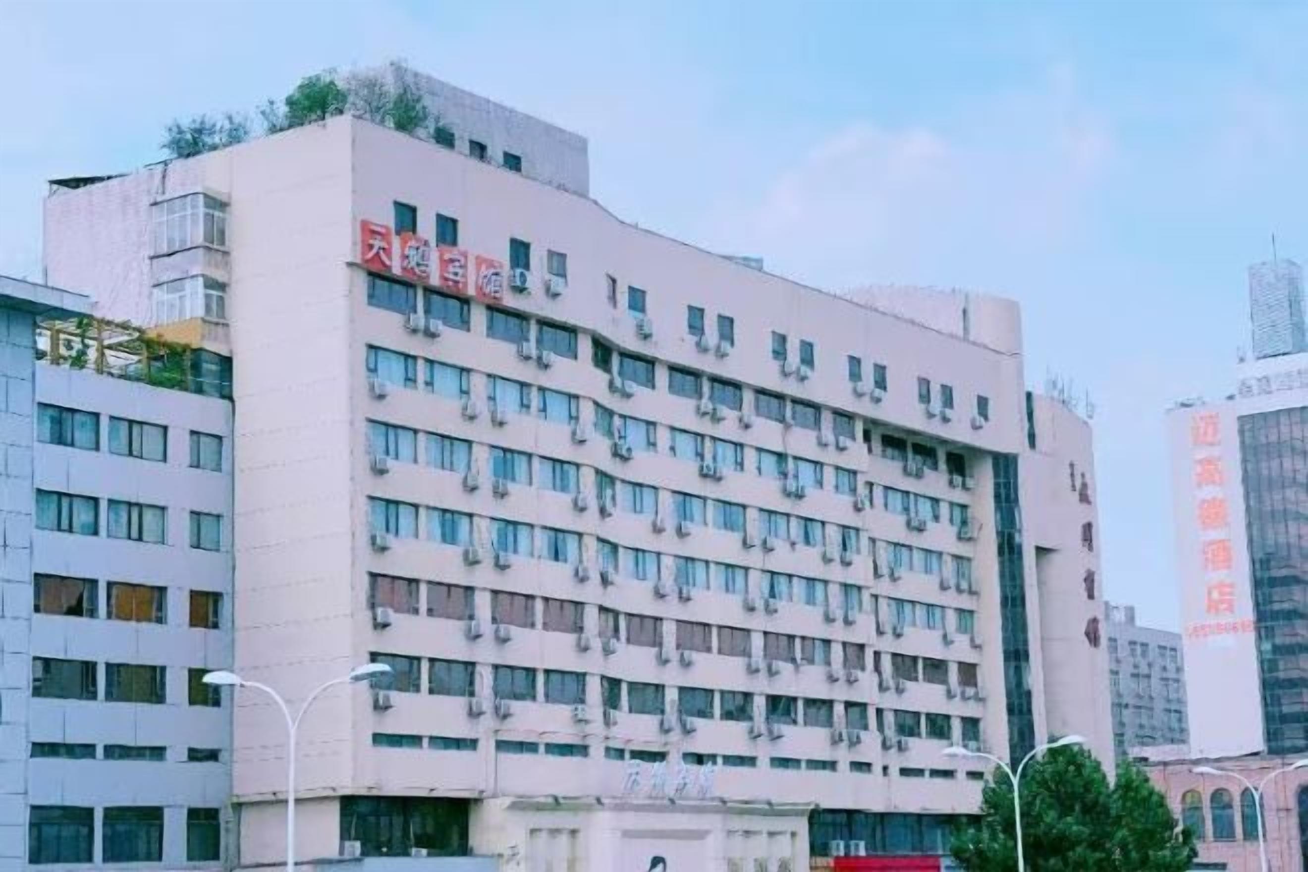 A multi-story building with a flat facade, numerous windows, and a prominent red sign on the upper level.