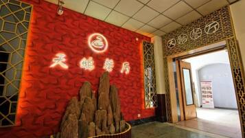 A hotel entrance with a red textured wall, a wooden display of rocks, and Chinese characters.