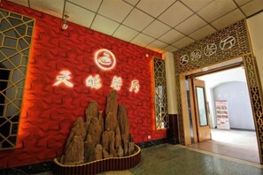 A hotel entrance with a red textured wall, a wooden display of rocks, and Chinese characters.