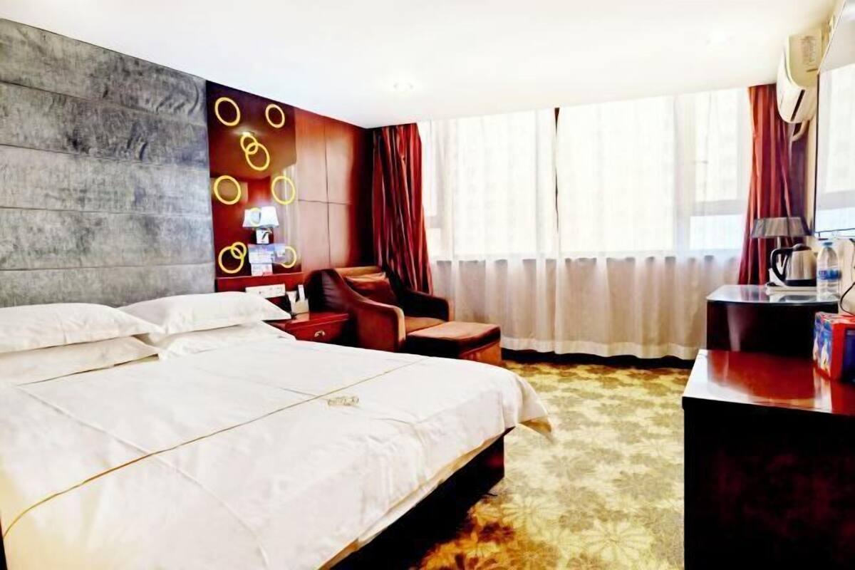 Una habitación de hotel con una cama grande, un escritorio con lámpara, una silla y una pared con lámparas circulares.