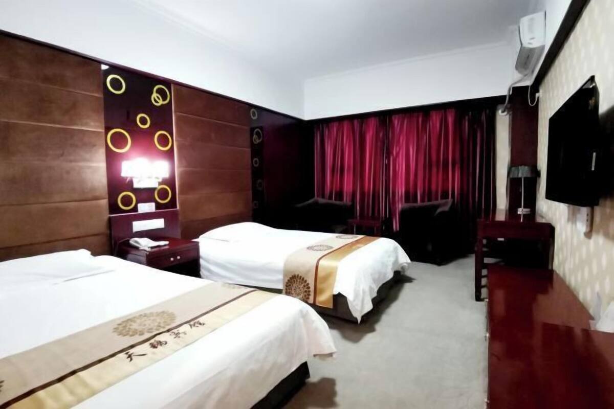 Una habitación de hotel con dos camas, televisión, escritorio y una silla.