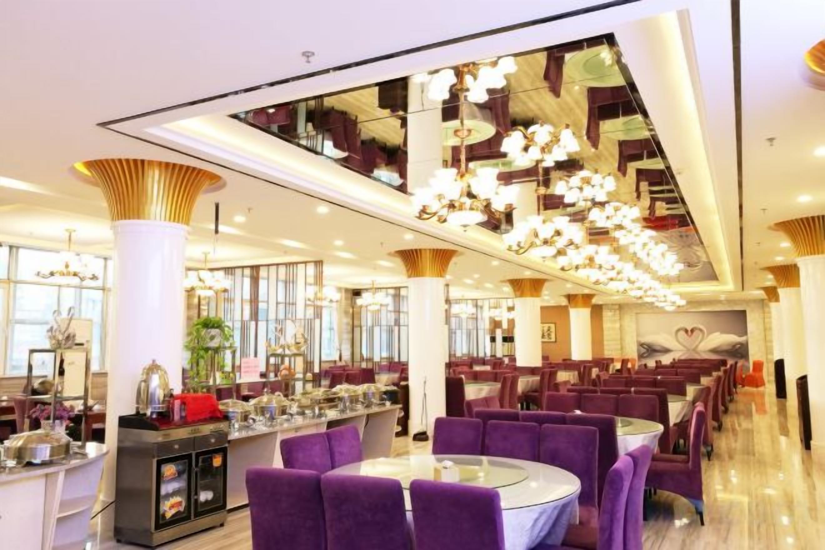 A spacious restaurant with high ceilings, modern chandeliers, and purple seating.