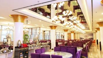 A spacious restaurant with high ceilings, modern chandeliers, and purple seating.
