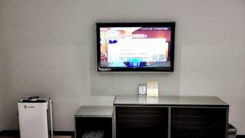 A television mounted on a wall, a white air purifier, and a wooden cabinet below the TV.