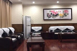 Une chambre d’hôtel avec un canapé, une table, un réfrigérateur et un tableau au mur.