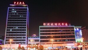 A multi-story building with illuminated signage, a pedestrian plaza, and surrounding commercial buildings.