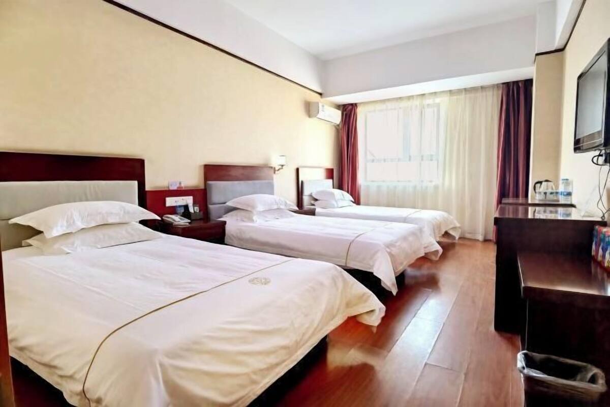 Habitación de hotel con dos camas, televisión, escritorio y un cesto de basura.