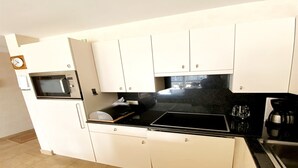 A compact kitchen with white cabinets, a microwave, a sink, and a coffee maker.