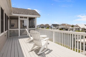 A wooden deck with rocking chairs and a small table, overlooking a body of water and neighboring houses. - Always Sunday-Pet Friendly Home in Atlantic Beach, NC (Atlantic Beach)