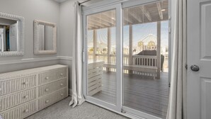 A room with a sliding glass door leading to a balcony, a white console table, and a mirrored wall. - Always Sunday-Pet Friendly Home in Atlantic Beach, NC (Atlantic Beach)