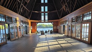 Amplio espacio interior con pisos de madera y grandes ventanales, con vistas a un lago.