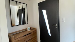 A modern room with a wooden dresser, a black door with a light strip, a mirror, and a small framed picture on the dresser. - New vacation home 5 minutes from the sea (Plobannalec-Lesconil)