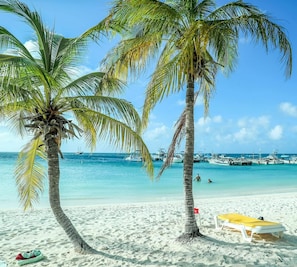 A beach with two palm trees, a sandy shore, and a clear blue sea. - 50m2 NEW condo Oranjestad - Rated 10/10 & 5-star - Arubaislanderresidence.com (Oranjestad)