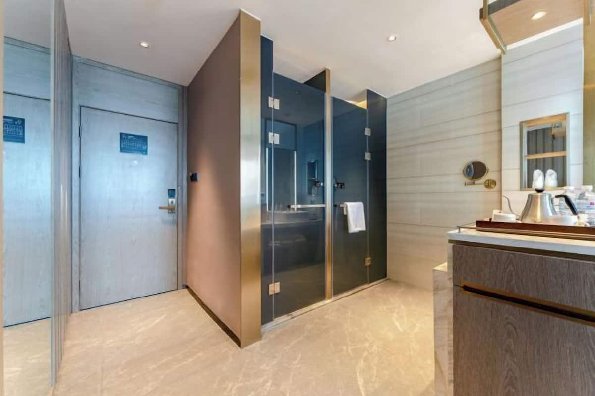A modern bathroom with a glass partition, a wooden vanity, and a mirror.