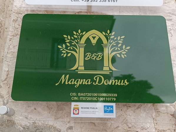 A green plaque with a logo and text for 'Magna Domus' and contact information.