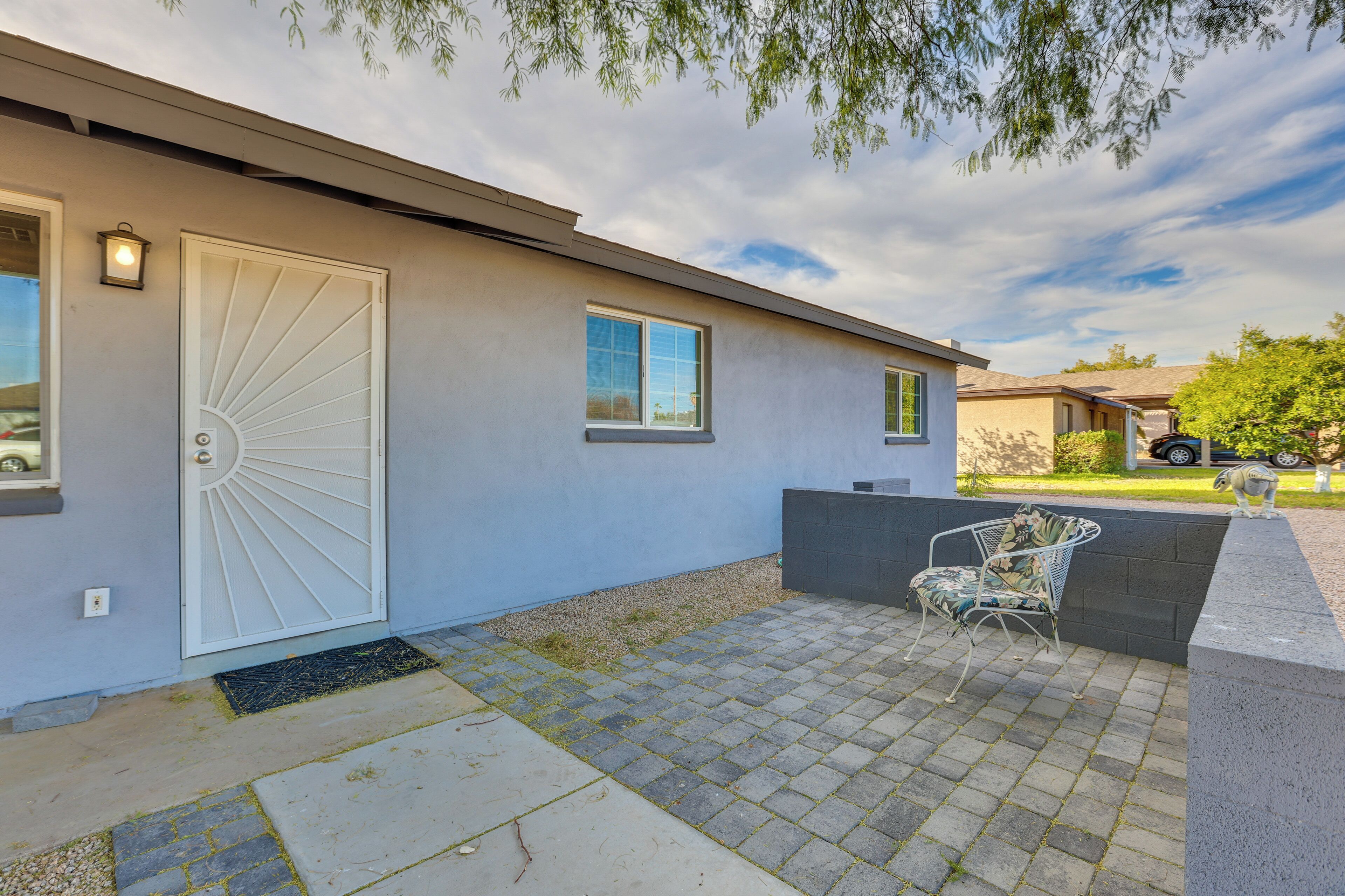 A modern house with a white door, a small patio with a chair, and a clear sky.